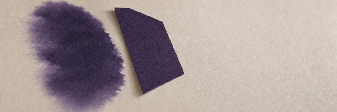 A soft violet ink bloom feathering into damp cotton paper, and beside it the same violet cut with a clean scalpel edge, raised enough to cast a thin shadow.